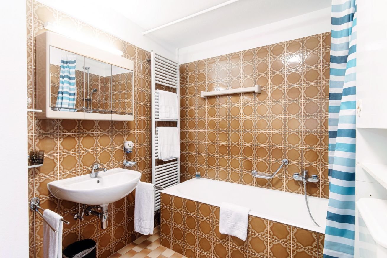 A bathroom with a sink, mirror, bathtub, and shower.
