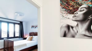 A bedroom with a wooden bed, a window with curtains, a radiator, and a painting on the wall. - Historic house in the artistic village of Brè (THE SECRET GARDEN) (Lugano)