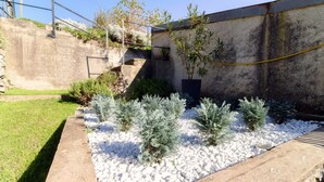 A garden with white gravel, small evergreen shrubs, and a potted plant. - Historic house in the artistic village of Brè (THE SECRET GARDEN) (Lugano)