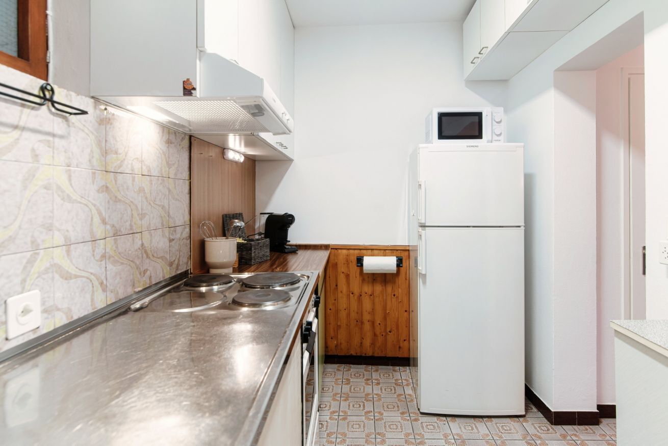 A compact kitchen with a stainless steel stove, a white refrigerator, and a microwave.