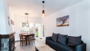A modern living room with a black sofa, wooden coffee table, and a dining area with chairs and a table. - Historic house in the artistic village of Brè (THE SECRET GARDEN) (Lugano)