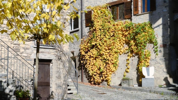 A stone building with ivy-covered walls and a staircase leading to an entrance. - Historic house in the artistic village of Brè (THE SECRET GARDEN) (Lugano)