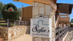 A sign for Sofia's Dreamy Retreat with a stone wall and a wooden fence.