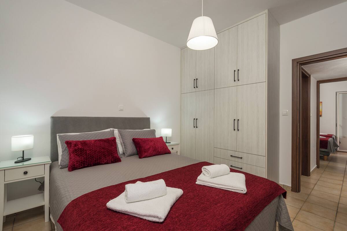 Een moderne slaapkamer met een groot bed, een witte garderobe en een hanglamp.
