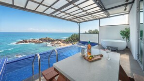 A balcony with a view of the ocean, a hot tub, and a table with a bottle and glass. - Yeongdeok Chaeumneul Poolvilla (Yeongdeok)