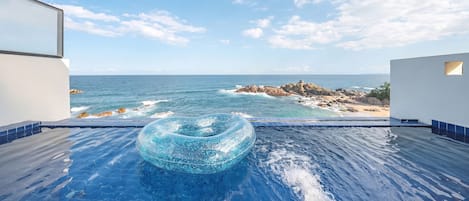 Una piscina con vista despejada al océano y a la costa rocosa.