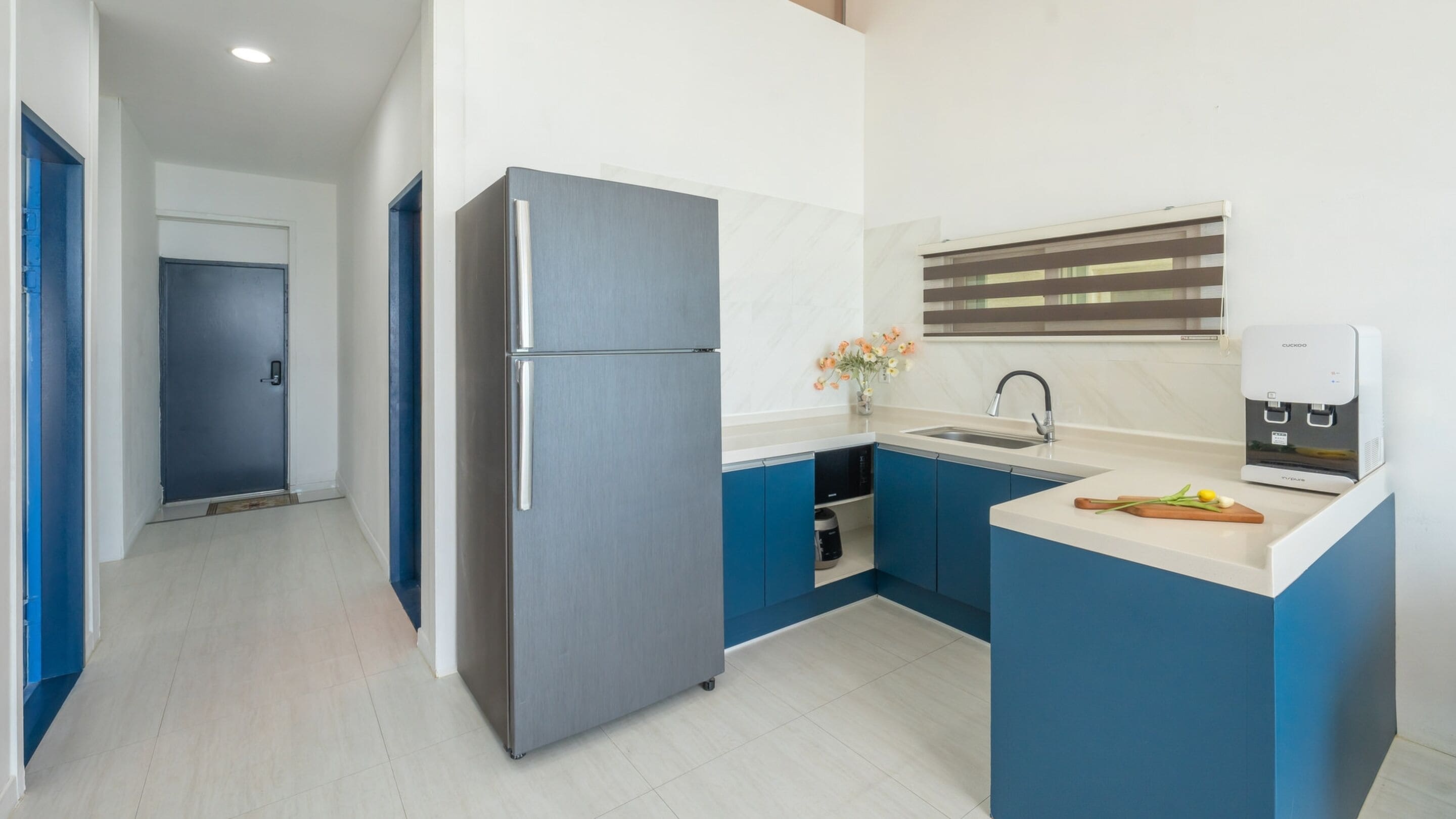 A modern kitchen with a built-in refrigerator, a sink, and a coffee machine.