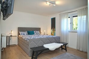 Una camera da letto con un letto, un comodino, una lampada e una finestra con tende.