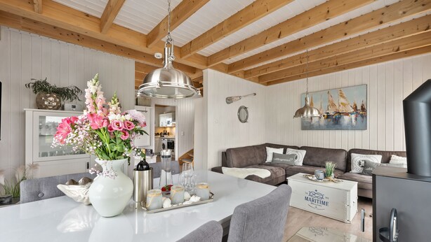 En moderne stue med træloft, et spiseområde med et hvidt bord og en brun sofa.