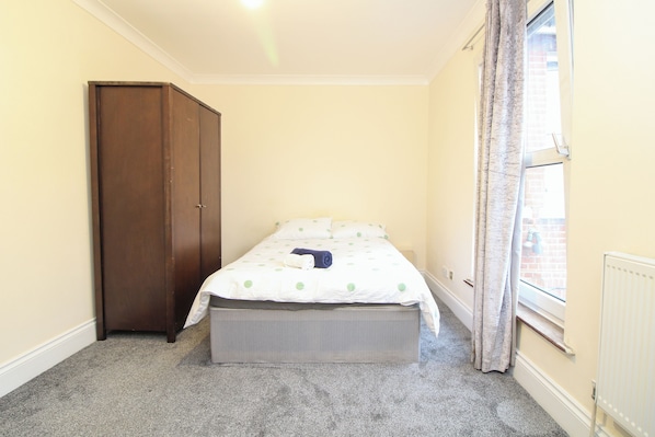 A bedroom with a single bed, a wardrobe, and a window with curtains. - Centrally located double room (Southampton)