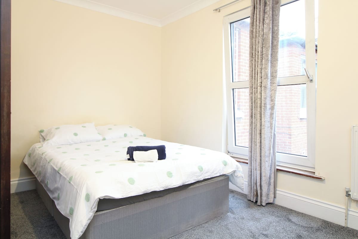 A bedroom with a bed, a window, and a radiator.