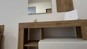 Une salle de bain moderne avec un meuble-lavabo en bois, un grand miroir et un plan de toilette blanc.