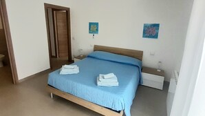 Une chambre à coucher comprenant un lit, une porte en bois, une table de chevet et deux œuvres d’art murales.
