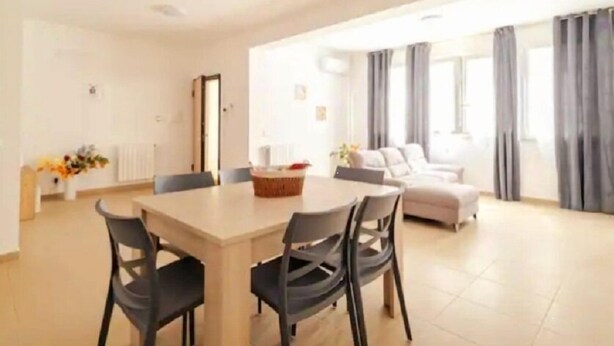 Un salon moderne comprenant un coin repas, un canapé et une grande fenêtre avec des rideaux.