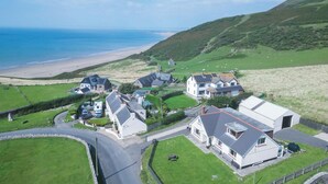 A coastal village with houses, a beach, and a road. - Carissima - 4 Bedroom House - Rhossili (Swansea)