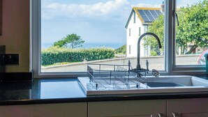 A kitchen with a window view of a house and a road. - Carissima - 4 Bedroom House - Rhossili (Swansea)
