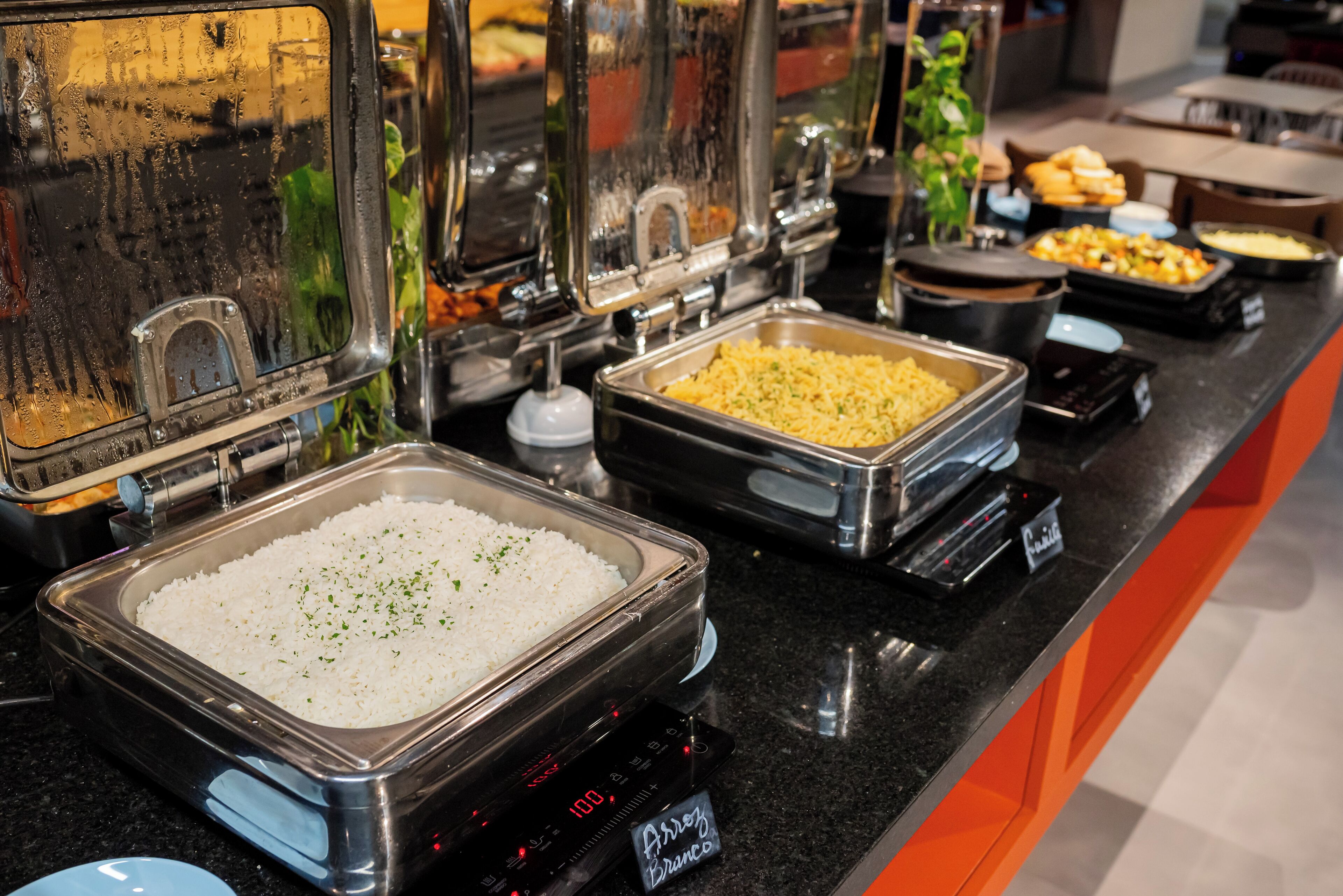 A buffet with various food options, including rice and other dishes in metal containers.