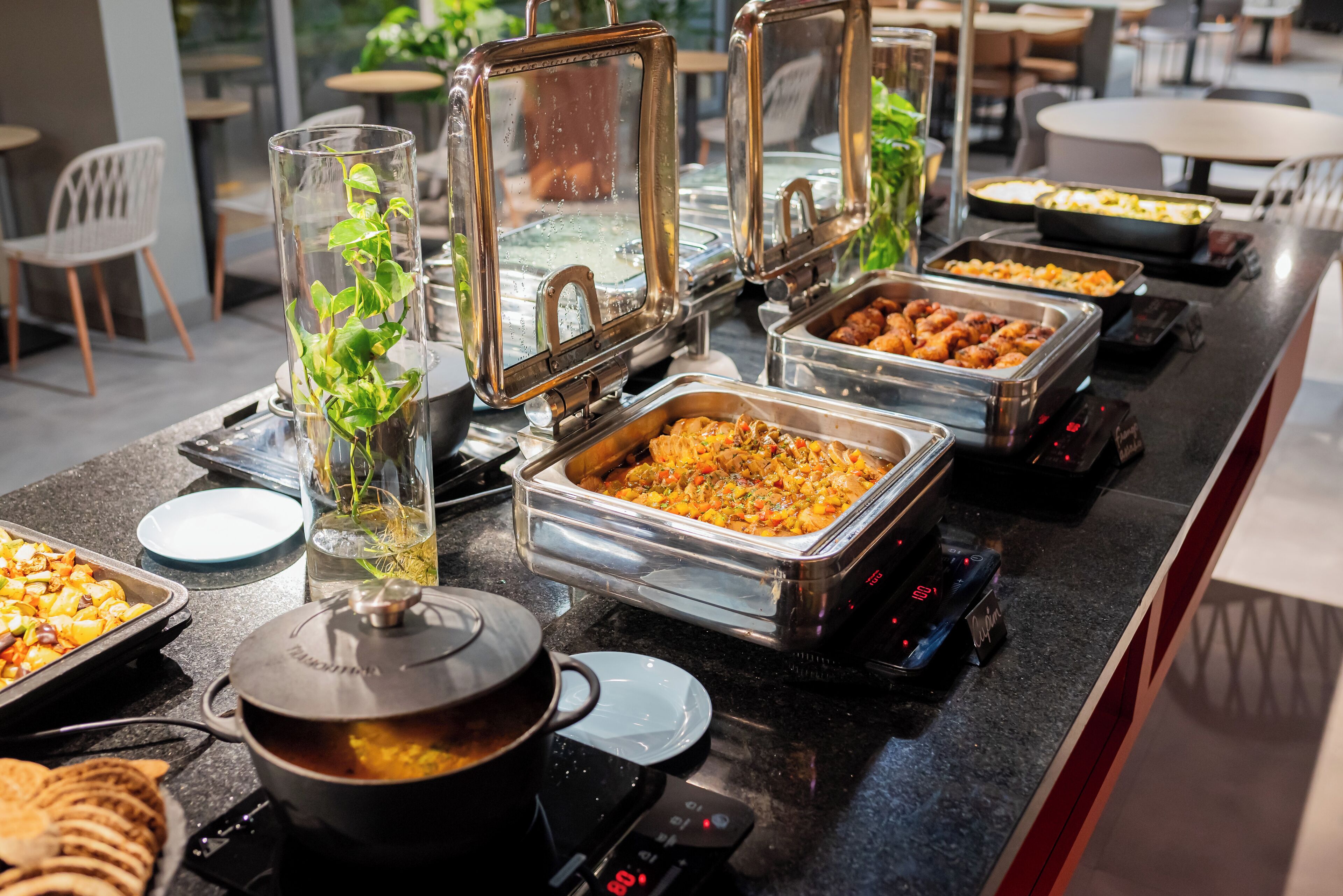 A buffet setup with various food items and a pot on an induction cooktop.