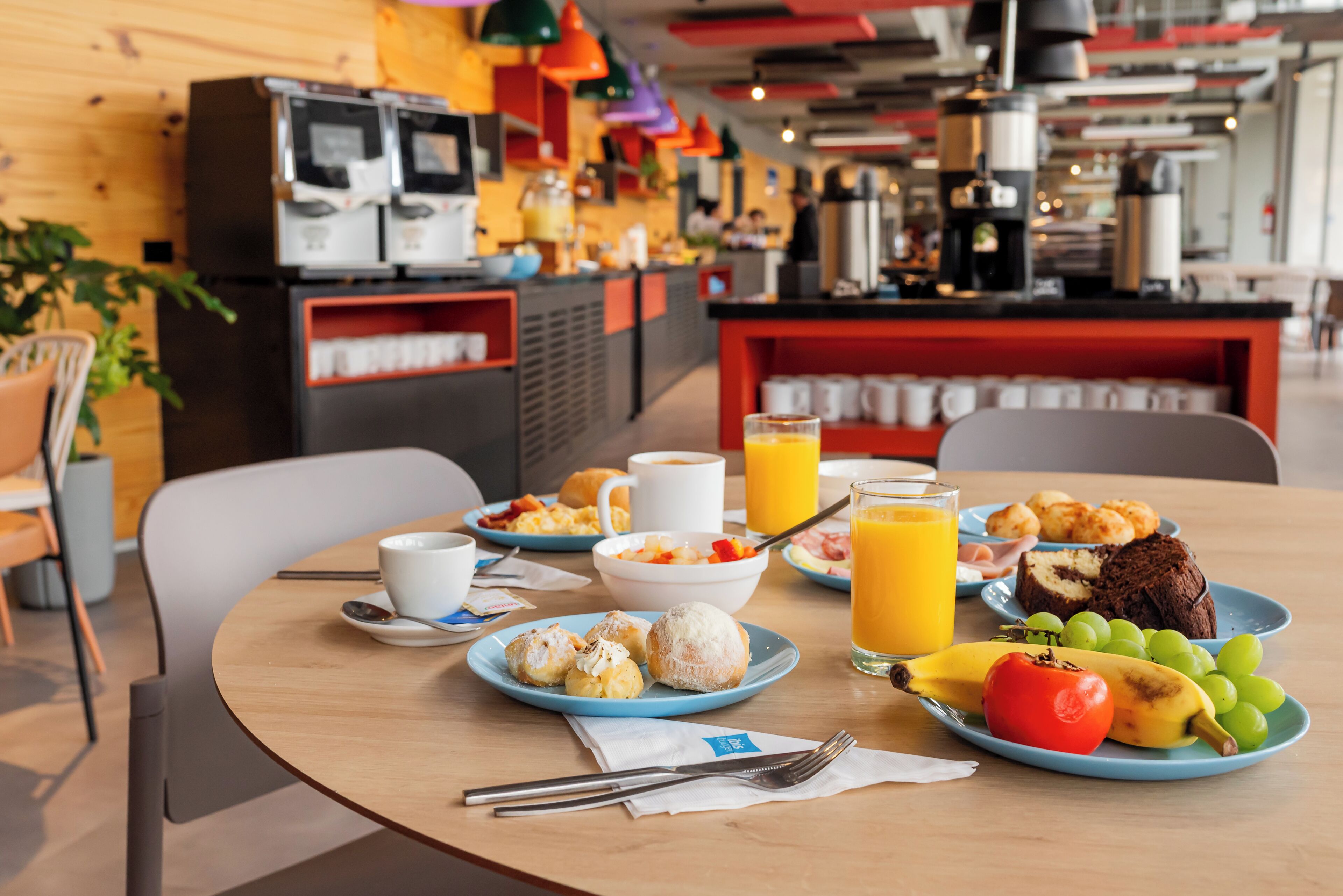 Una escena de desayuno con platos de comida, una máquina de café y un dispensador de jugo.