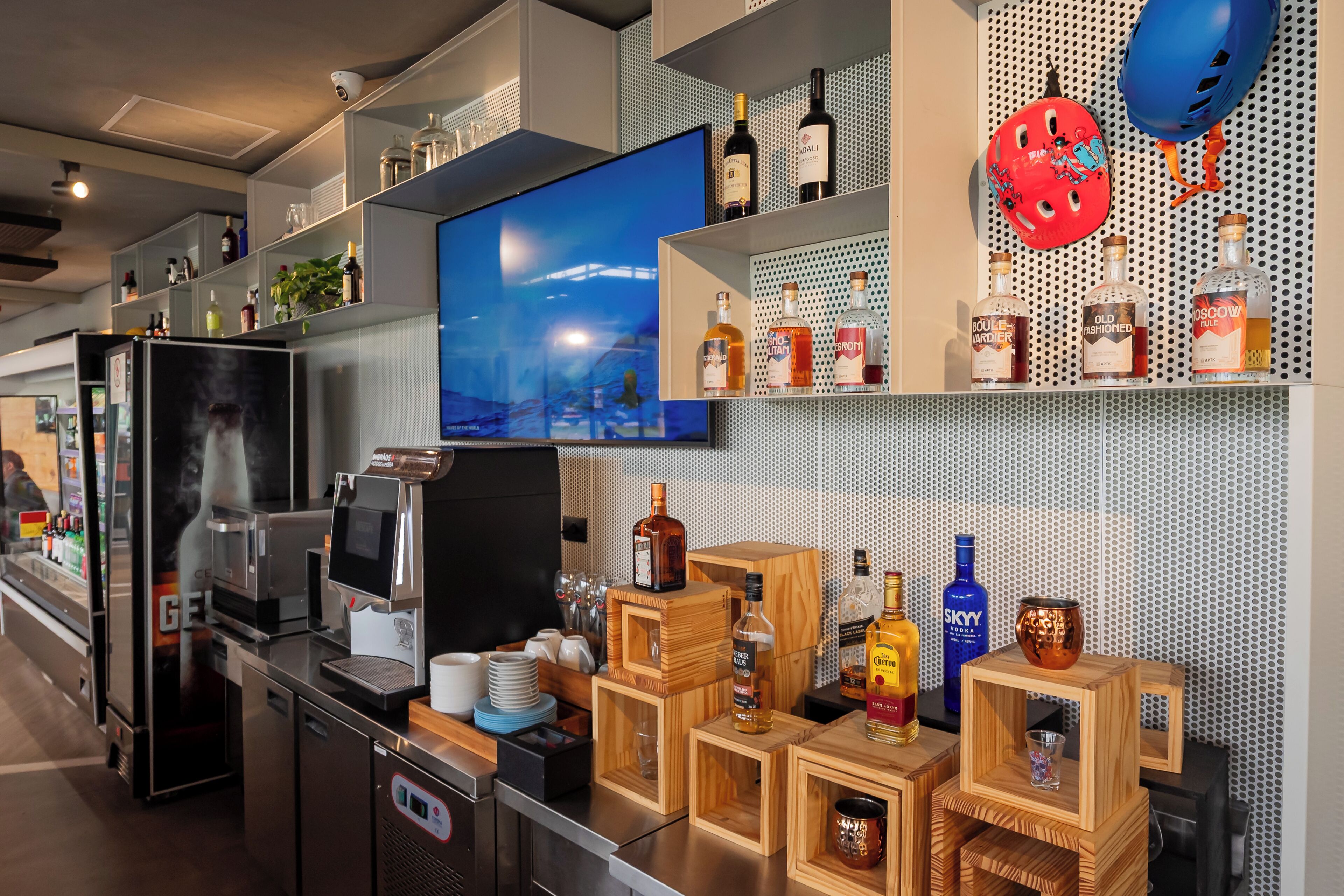 Un área de bar moderna con televisor, varias botellas de licor y cajas de madera para almacenaje.