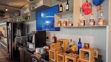 Un área de bar moderna con televisor, varias botellas de licor y cajas de madera para almacenaje.