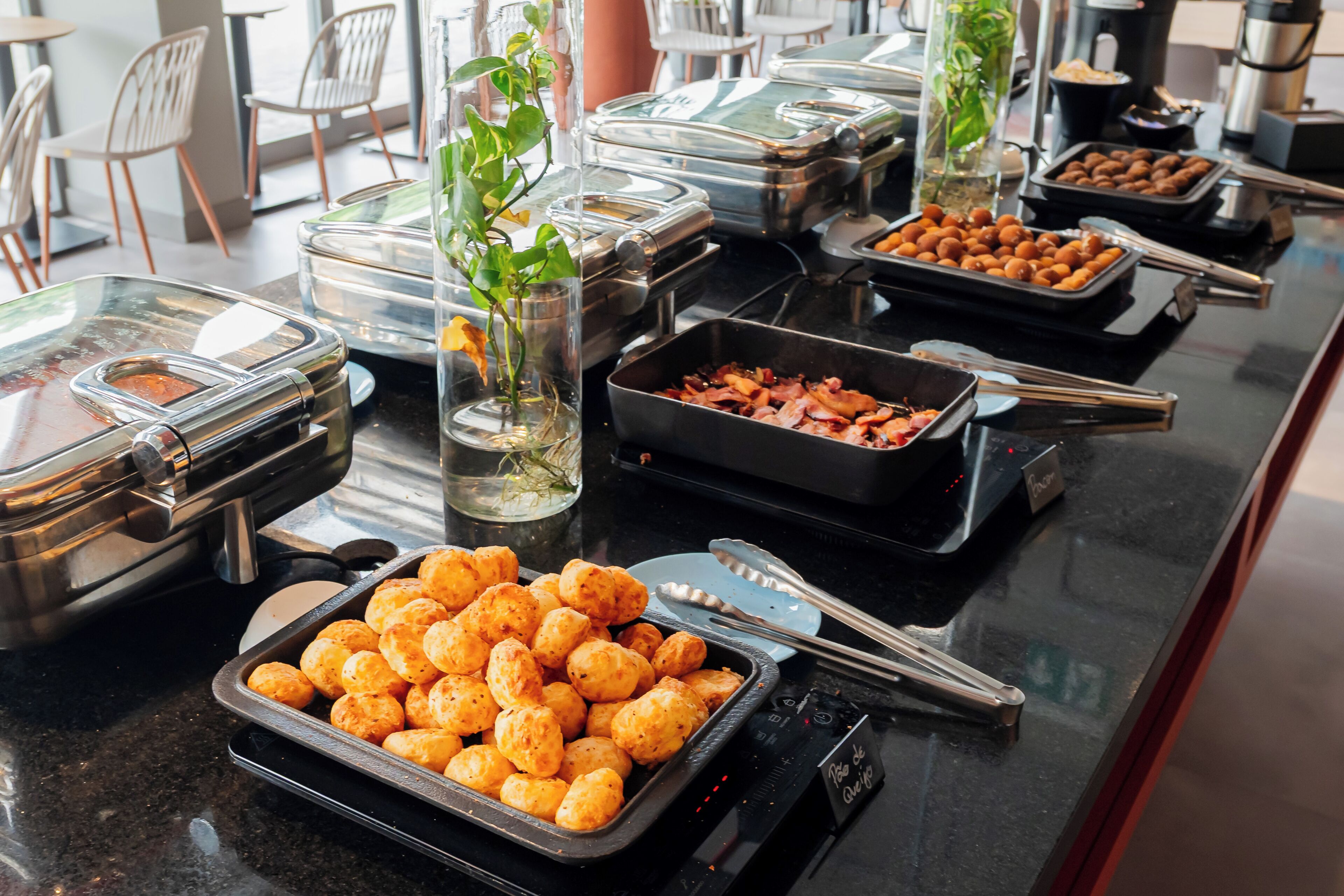 A buffet with various food items, including trays of cheese curds and bacon, and several glass containers with food.