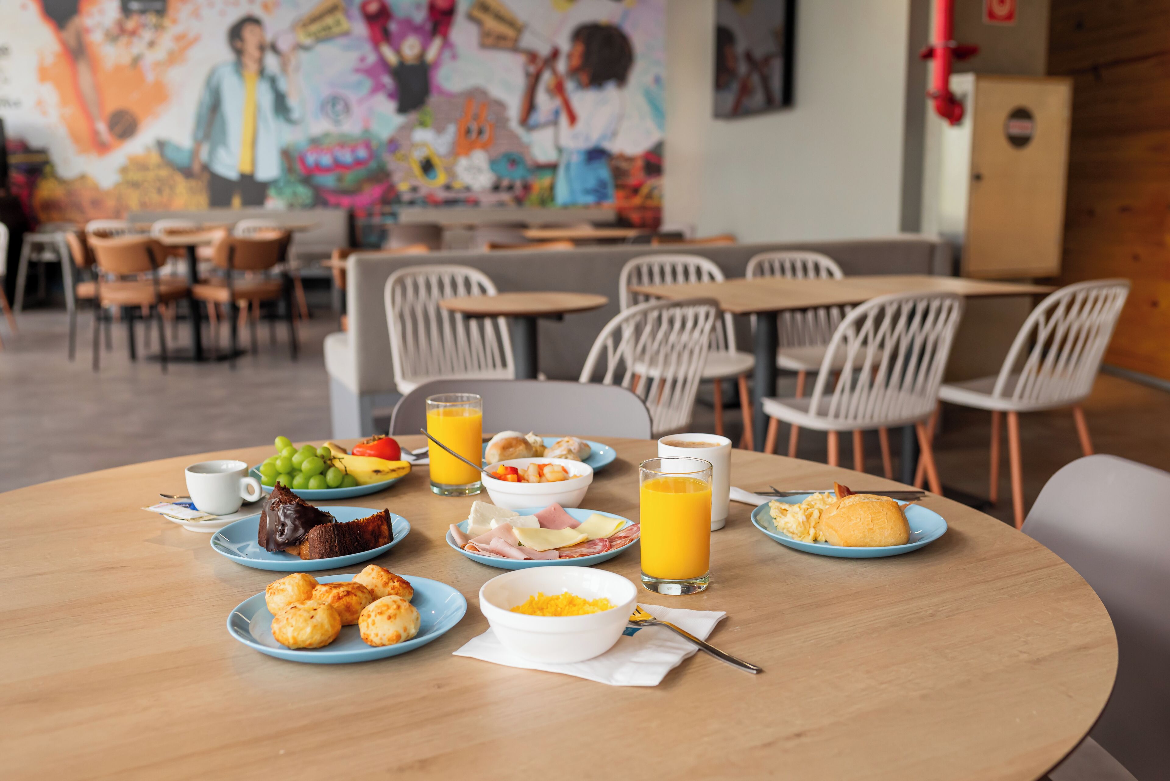 A breakfast table with plates of food, glasses of orange juice, and a bowl of cereal.