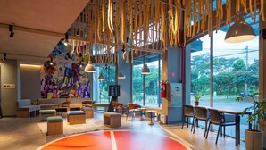 Un interior moderno con un mural colorido, zonas de estar y amplios ventanales que ofrecen vistas al exterior.