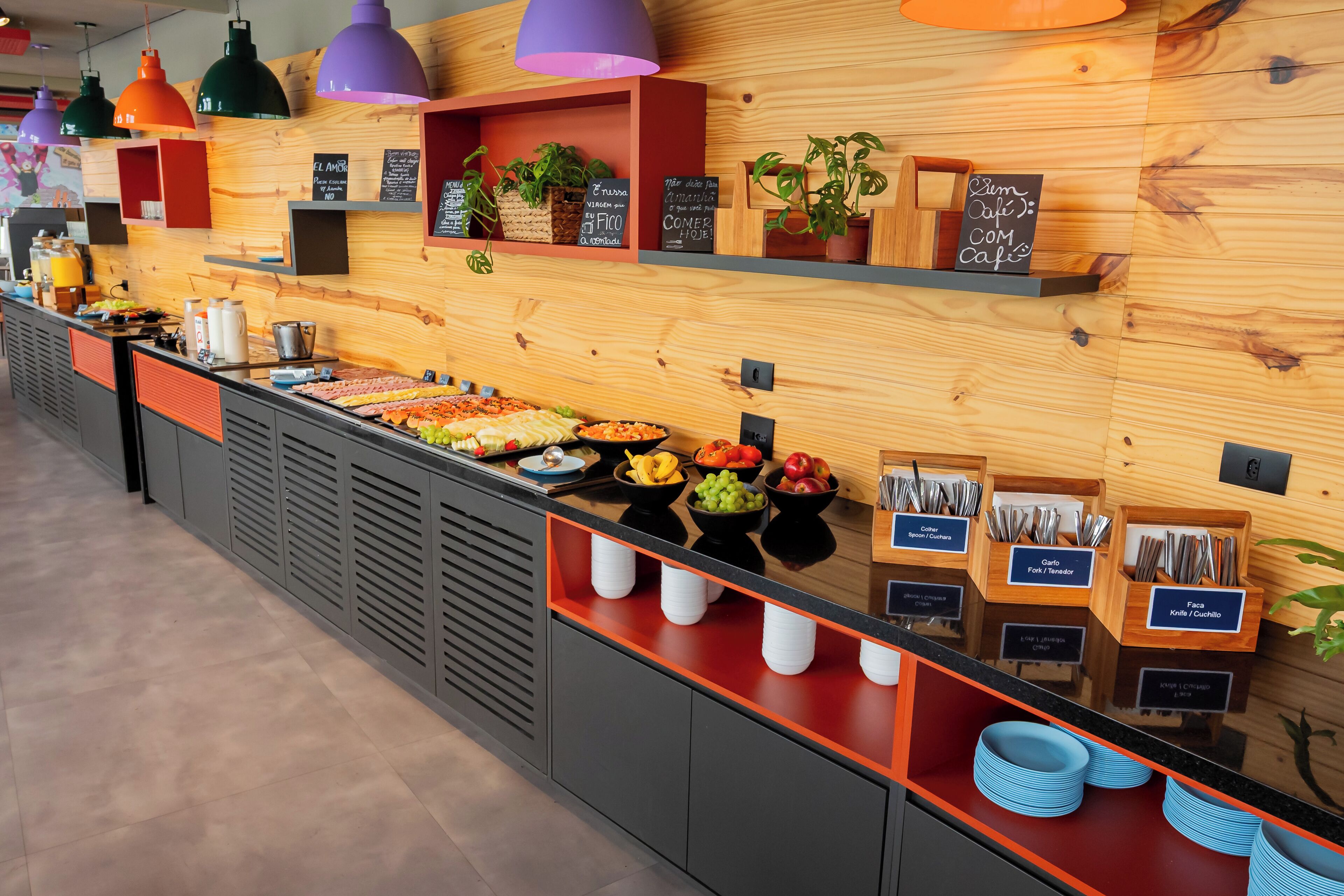 Un área de bufé con diversas opciones de comida, utensilios y plantas decorativas.