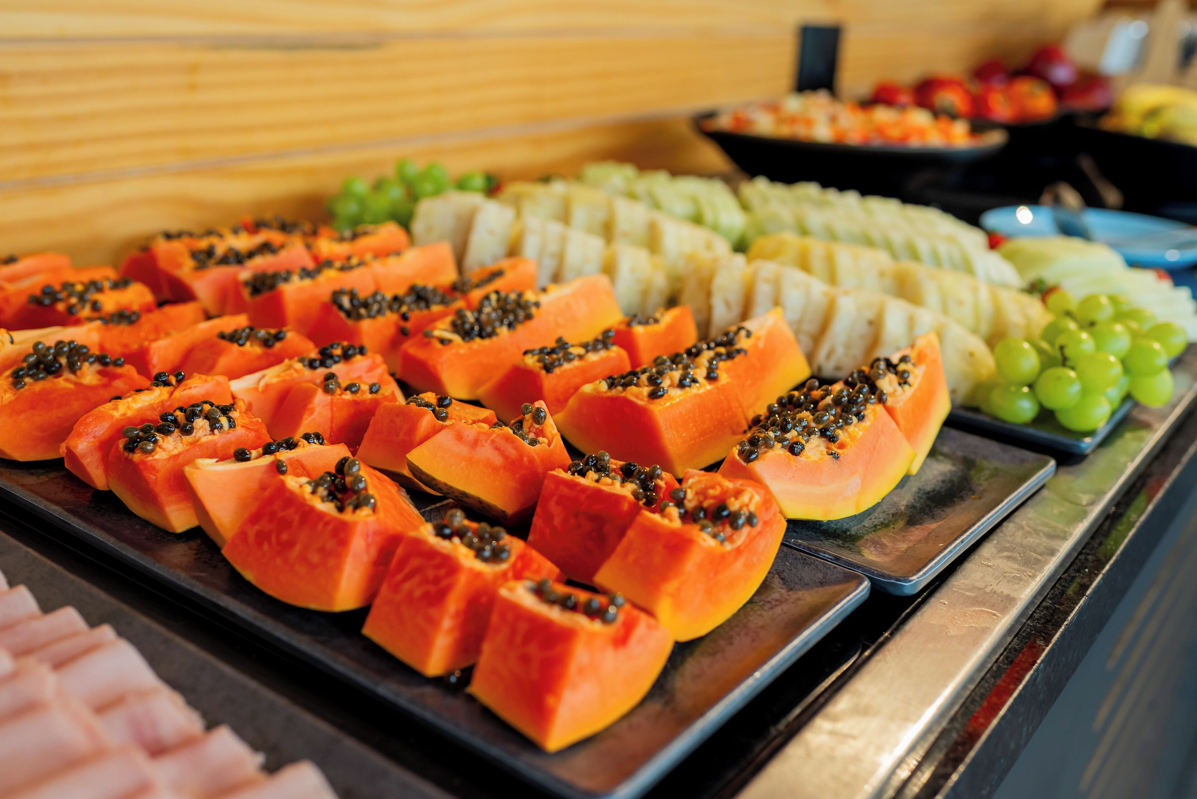 A buffet with various fruits including papaya, bananas, and grapes.