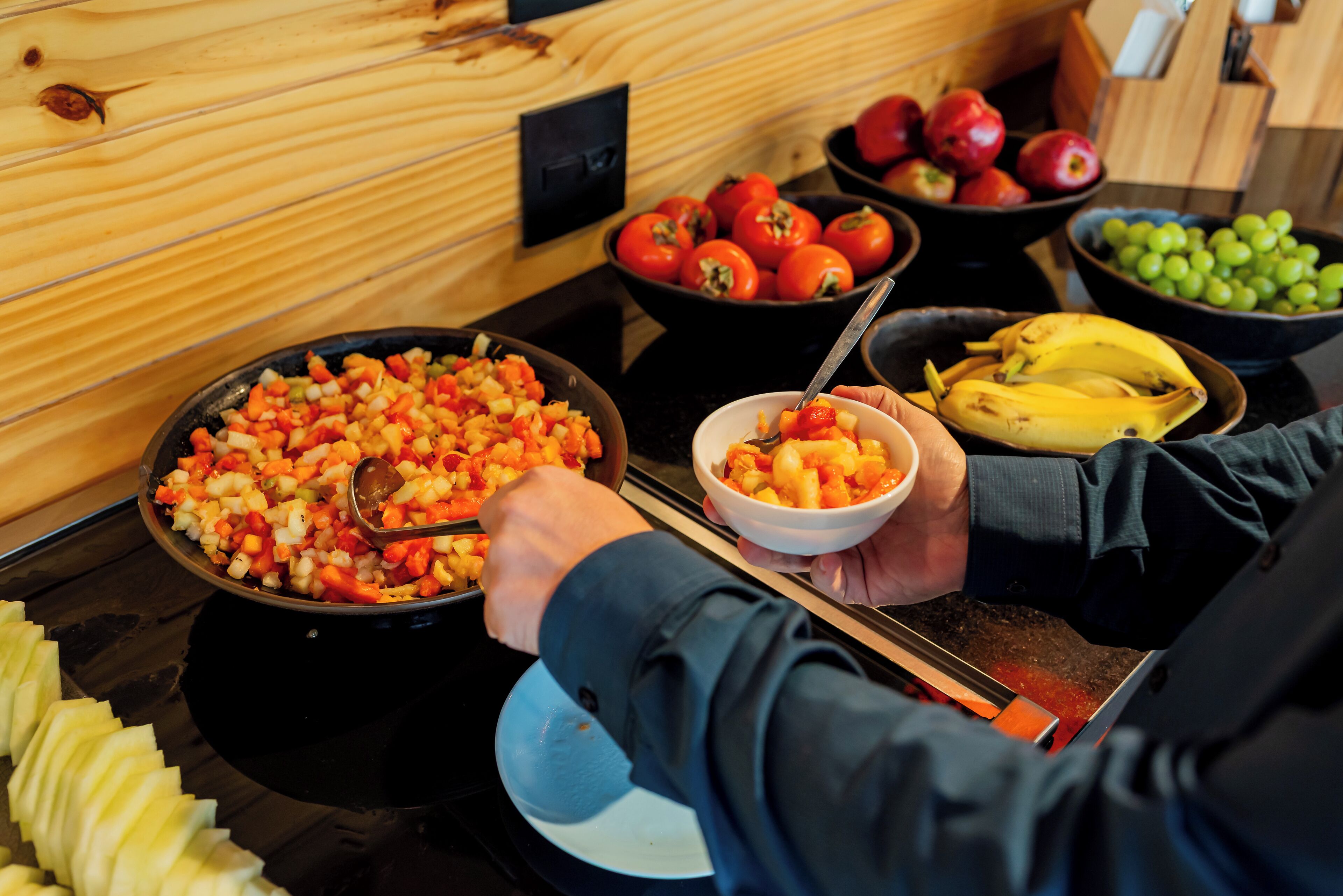 Een buffet met verschillende soorten fruit en groenten, zoals tomaten, appels en bananen.