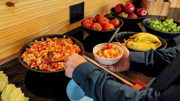 Een buffet met verschillende soorten fruit en groenten, zoals tomaten, appels en bananen.