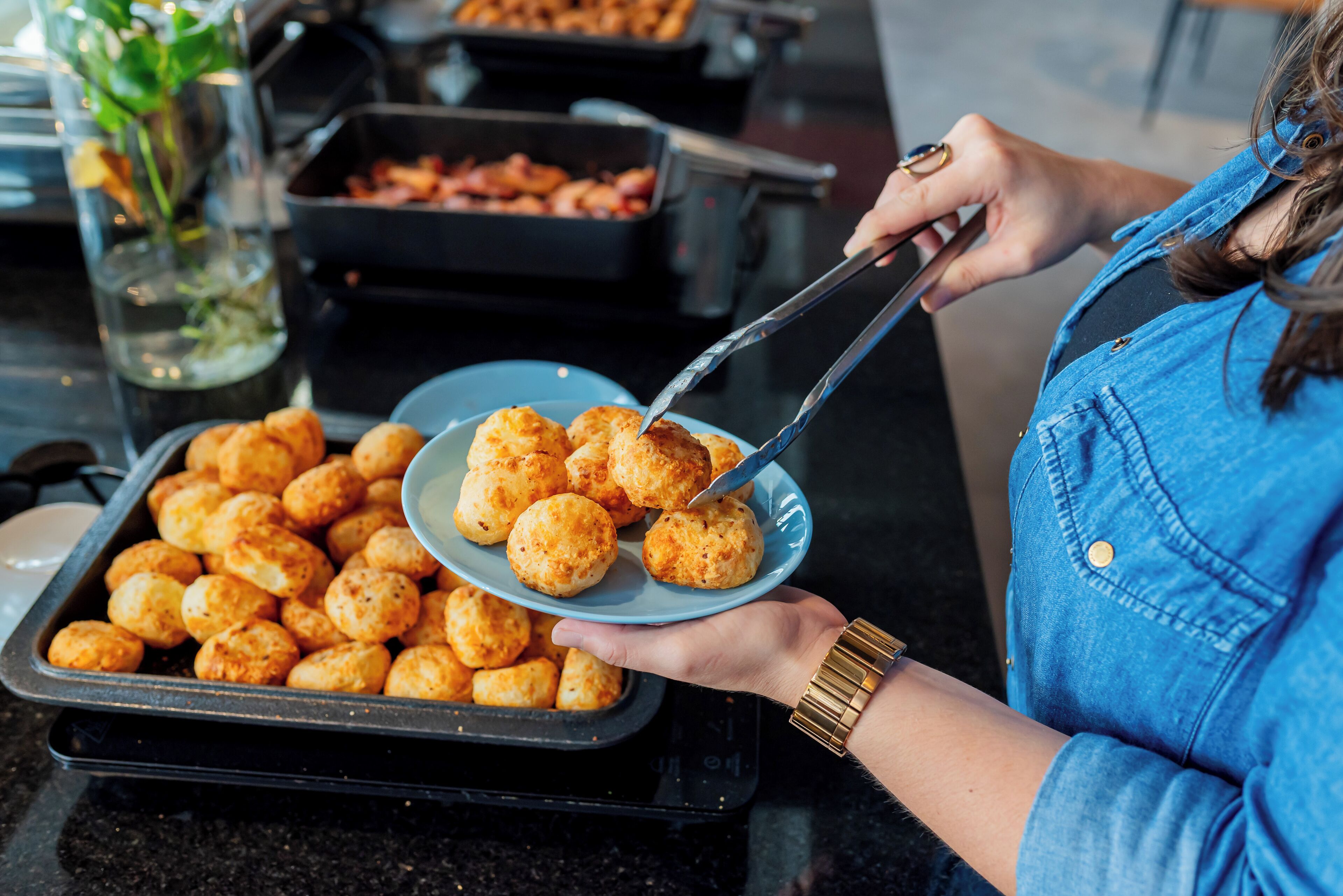 A person serving cheese balls from a tray to a plate.