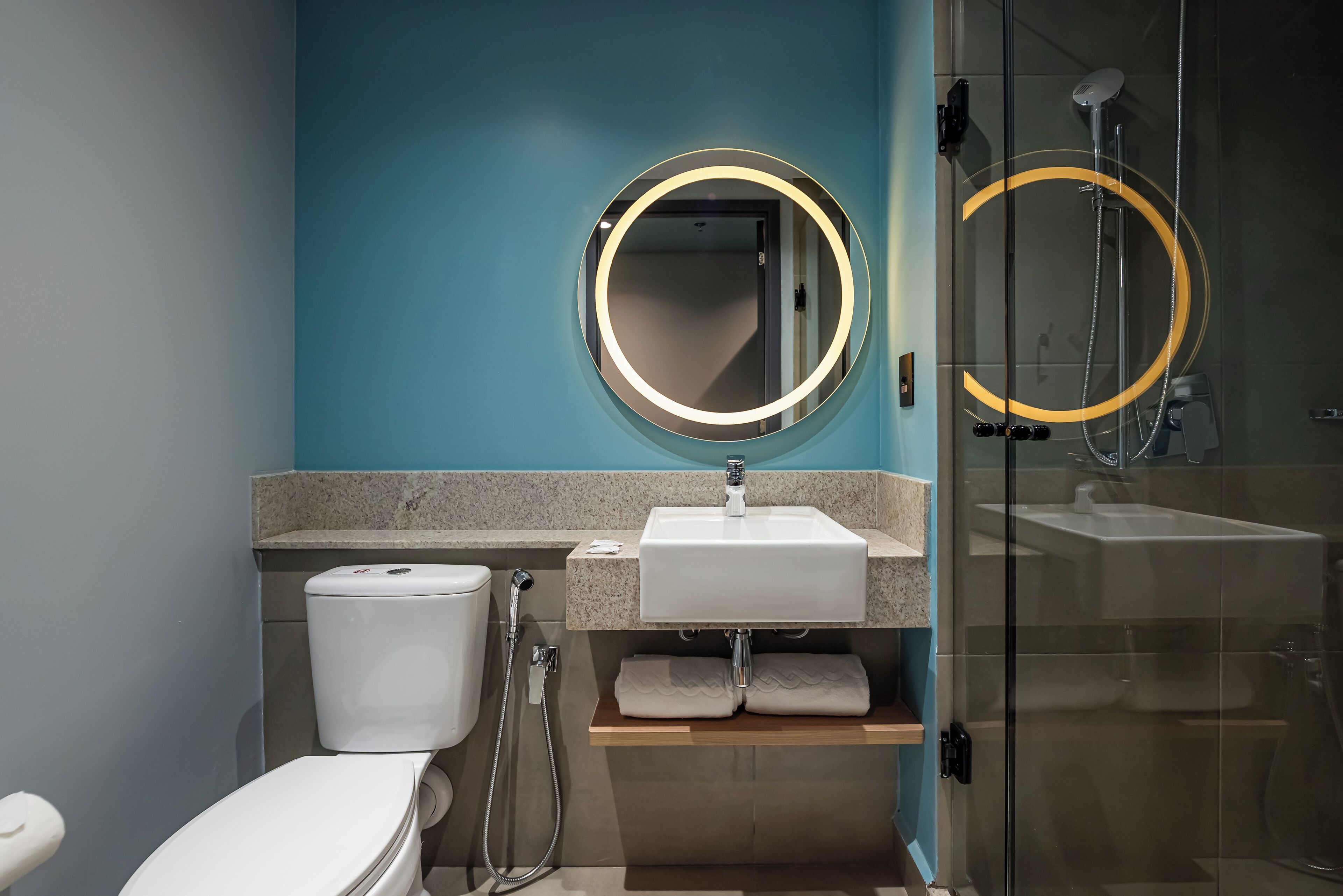 A modern bathroom with a toilet, sink, and glass shower enclosure.