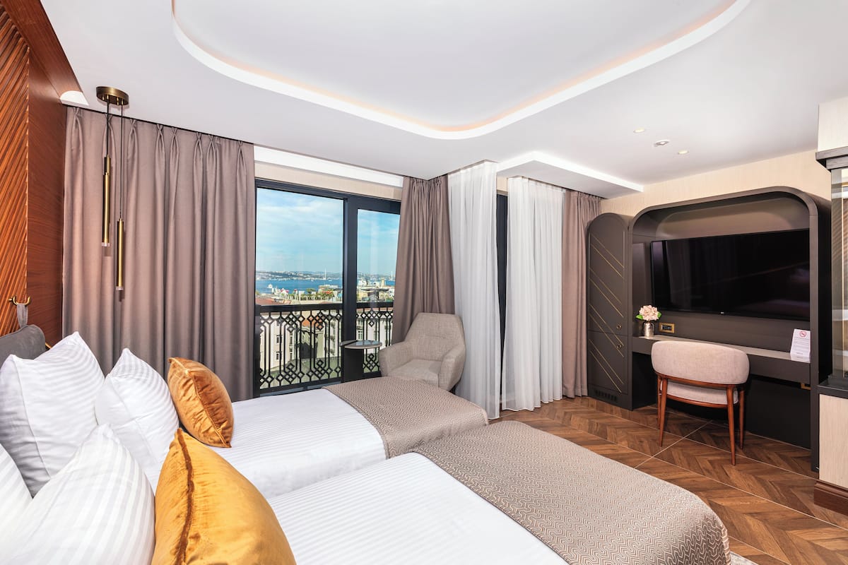A hotel room with a large window, a bed, a desk, and a chair.