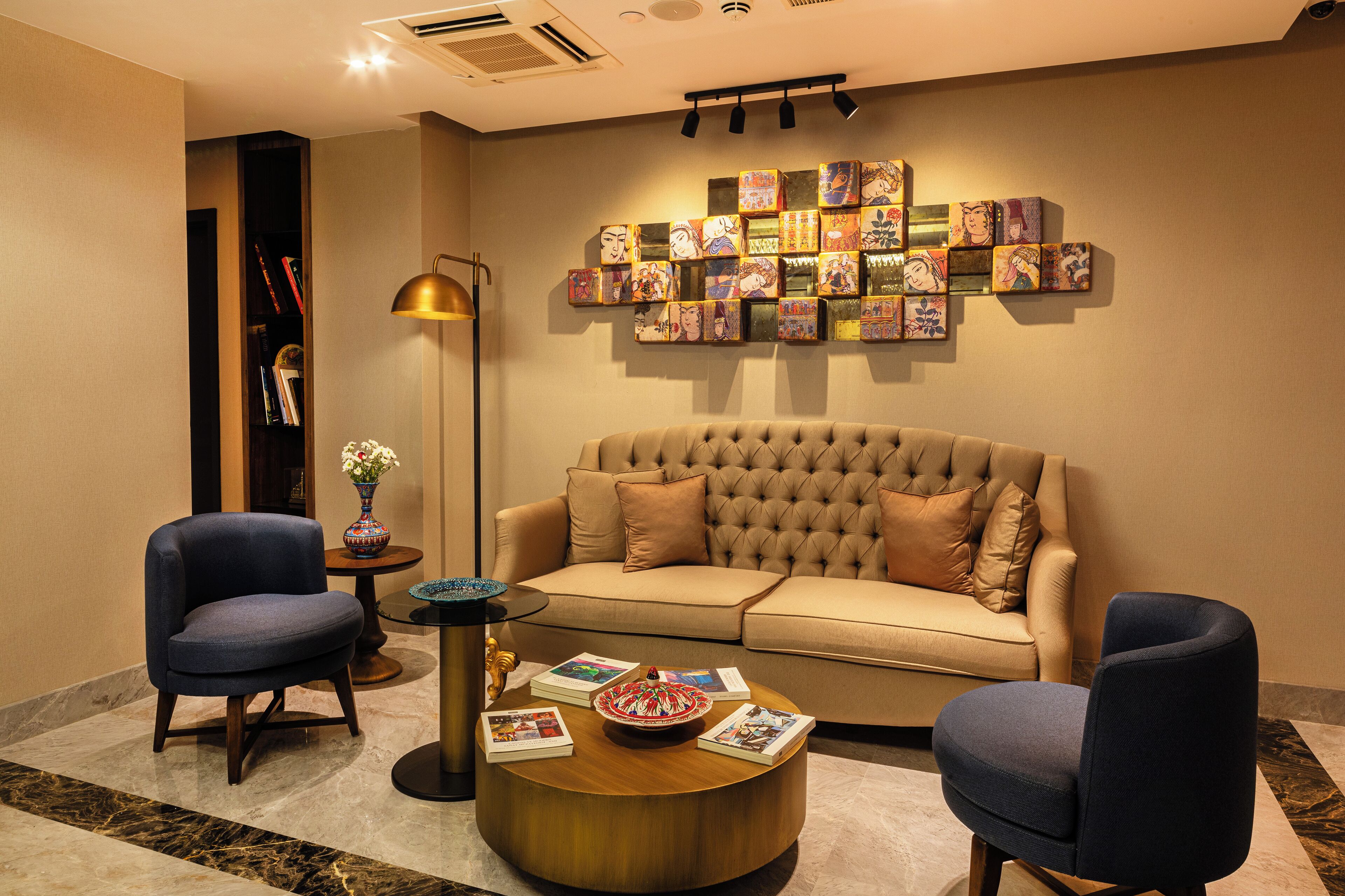 Un salon moderne avec un canapé capitonné, deux fauteuils, une table basse et une décoration murale.