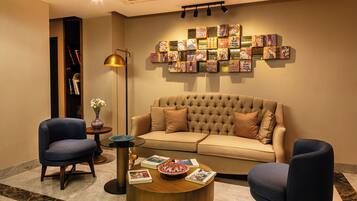 Un salon moderne avec un canapé capitonné, deux fauteuils, une table basse et une décoration murale.