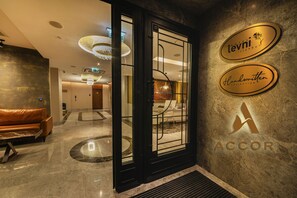 A hotel lobby with a reception desk, a leather sofa, and a chandelier. There are signs for 'Levi' and 'Handwritten Collection'. - Levni Istanbul Hotel Handwritten Collection (Istanbul)