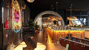 Uma área de bar com mesa de futebol de mesa, um letreiro neon e vários instrumentos musicais.