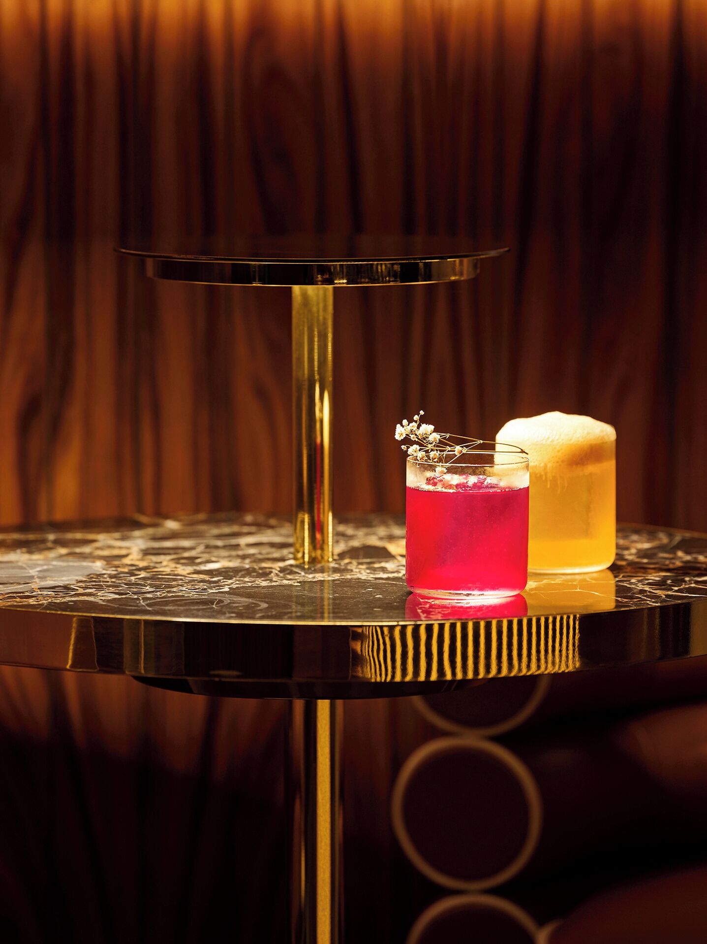 A bar area with a round table, a tall glass, and a bottle.
