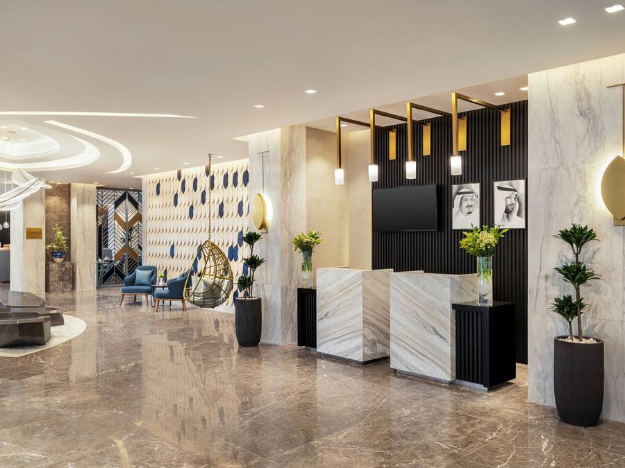 A modern lobby with a marble floor, seating area, reception desk, and decorative wall panels.