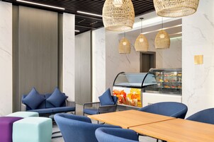 A modern cafe with blue seating, a wooden table, and a bakery display.