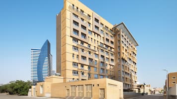 Um edifício de vários andares com design arquitetônico moderno, destacando uma entrada imponente com degraus e um telhado plano.