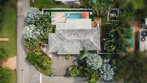 An aerial view of a hotel with a rooftop pool, multiple lounge areas, and lush landscaping. - Towering Palms in Wilton Manors (Wilton Manors)