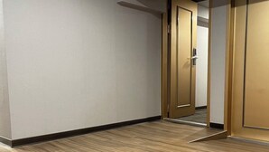 Een hal met houten vloeren, een plafondprojector en een deur naar een andere kamer.