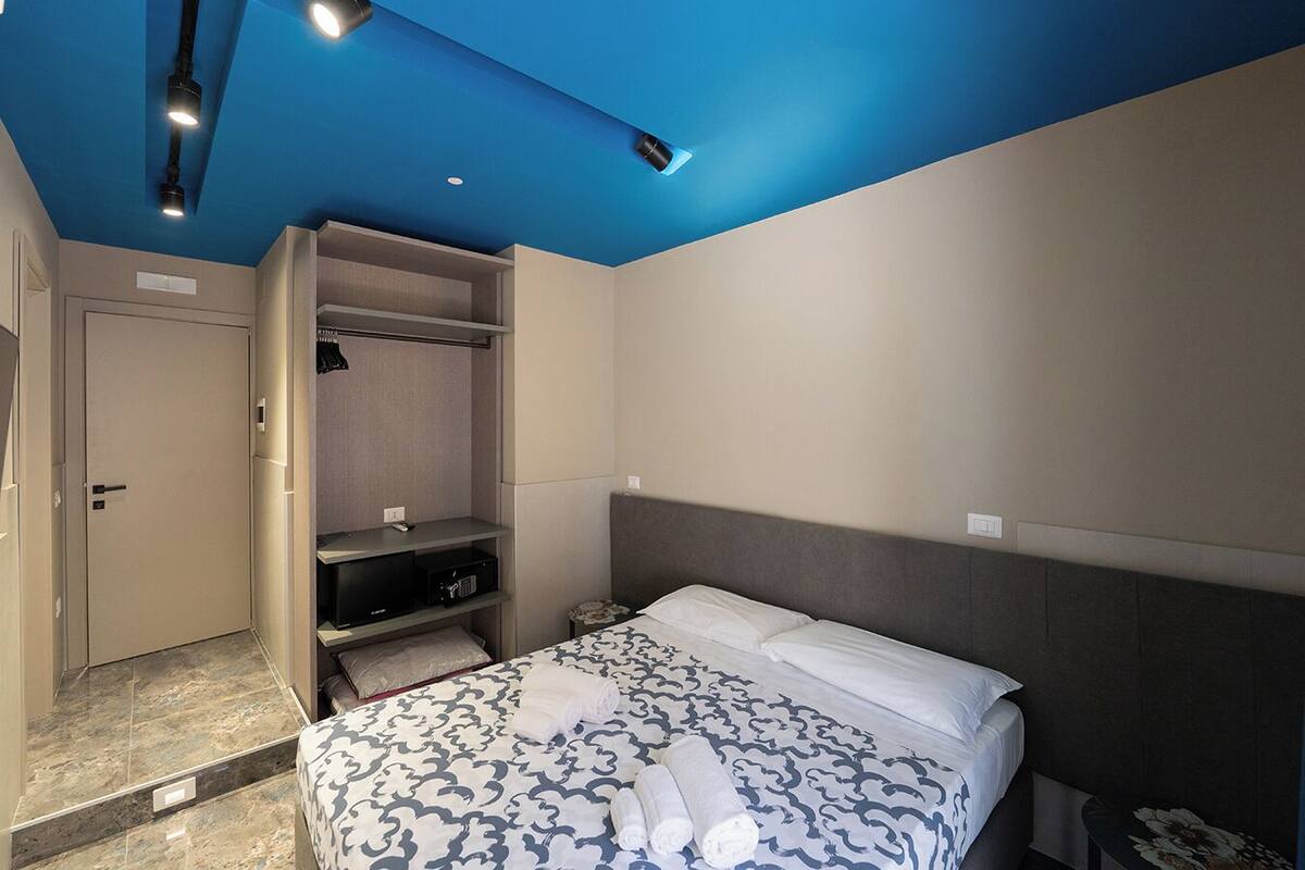 A hotel room with a bed, a wardrobe, and a desk.