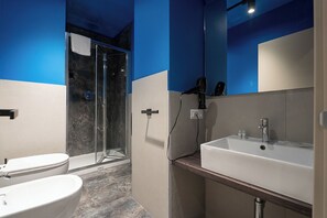 Un baño moderno con cabina de ducha de vidrio, un lavabo blanco y un inodoro.