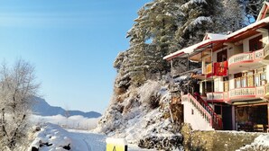 A snow-covered landscape with a building featuring a balcony and a sign for 'The Yellow Chalet'. - Fresh View Homestay (Sainj)