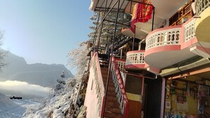 A building with a balcony, a staircase, and a view of snow-covered mountains. - Fresh View Homestay (Sainj)