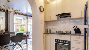 A modern kitchen with white cabinets, a built-in oven, and a coffee maker. - Casa Amore Aqua Sol (Vagator)
